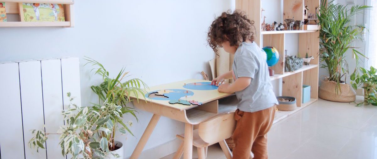 Niño explorando materiales en una estantería baja de un ambiente preparado